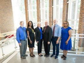 Six members of the grant writing team for the Noyce scholarship program stand in the George Hall lobby